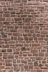 Alte Mauer aus vielen groben viereckigen roten Sandsteinen in Nahaufnahme Hochformat