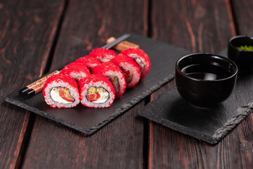 California sushi roll with salmon, avocado cucumber and tobiko caviar served on black board close-up - Japanese food