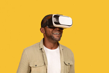 Cheerful middle aged african american man gamer in casual and vr glasses enjoy online game and virtual world