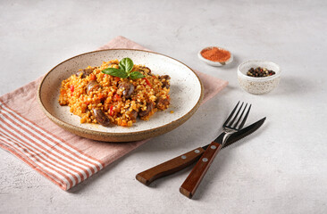 bulgur with chicken hearts and vegetables. Delicious healthy dish on a gray background. Bulgur pilaf