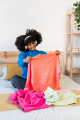 Cheerful black girl in bedroom browsing her clothes