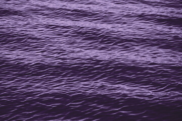 The rippled surface of the turbulent wavy sea in purple color