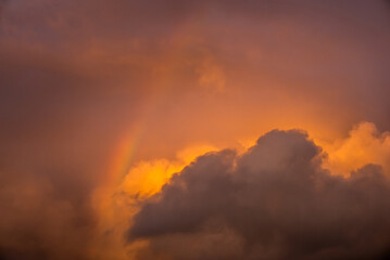 Beautiful cloudy skies with a colourful rainbow at sunset