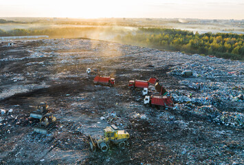 Garbage truck unloads rubbish in landfill. Landfill waste disposal on sunset. Garbage dump with waste plastic and polyethylene. Reduce gas emissions and methane emissions. Environmental protection.