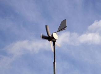 A small wind turbine on a cold, windy day with clouds in the background
