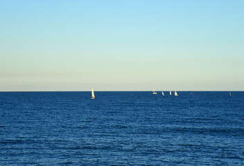 Obraz premium Sailboat at sea on sailing on the waves. Yachtsman during training on a sailboat. Skiff and Sailboat in sea port near the Spanish coast. Sail sport in Yacht club. Sail boat on waves on sunset in sea.