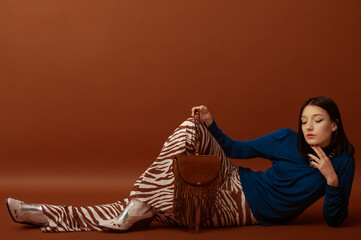 Fashionable confident woman wearing stylish blue turtleneck, trendy flared trousers with zebra...