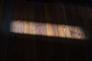 Narrow ray of sun on hardwood floor.