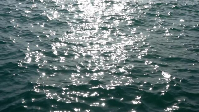 Water waves rippling on a summer day, sun reflecting off the surface