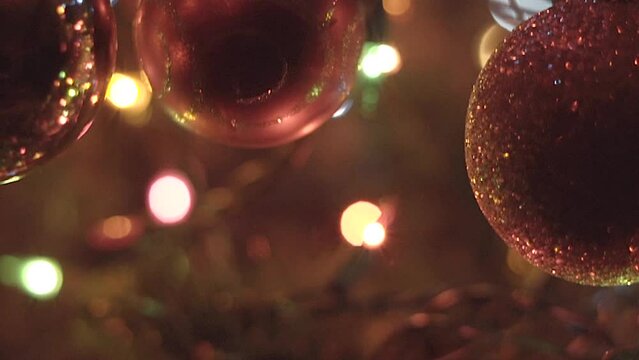 Christmas macro shot of ornaments on christmas tree during holiday season, with lights flickering in background
