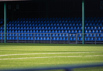 Seven rows of blue seats by a football pitch.