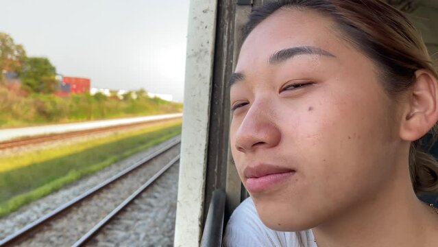 Happy young beautiful asian woman enjoy train ride cinematic nature view blue sky slow motion holding cellphone in hand taking picture. Tourism and holiday concept, Thailand