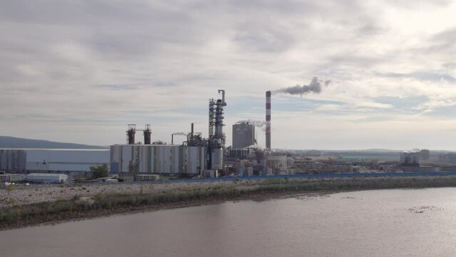 Smoking Stack of an Industrial Manufacturing Plant Next to a River