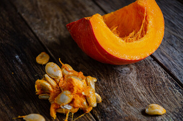 Разрезанная тыква и ее семена на деревянных досках.