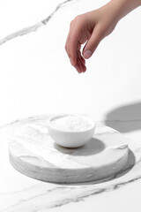 Hand spilling sea salt on white background