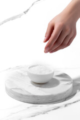 Hand spilling sea salt on white background