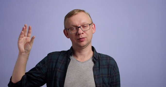 Man in glasses doing bla bla gesture against blue background, studio shot