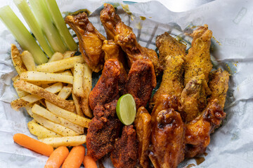 Chicken wings of different flavors with French fries, celery and carrot.