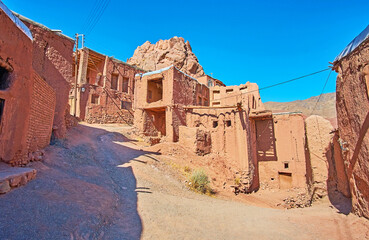 The fork on medieval hilly road with a view on old shabby adobe buildings of famous red village,...