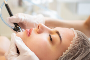 Obraz na płótnie Canvas Closeup headshot of young woman receiving hydrafacial therapy at beauty spa