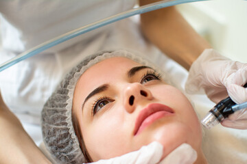Obraz na płótnie Canvas Closeup headshot of young woman receiving hydrafacial therapy at beauty salon