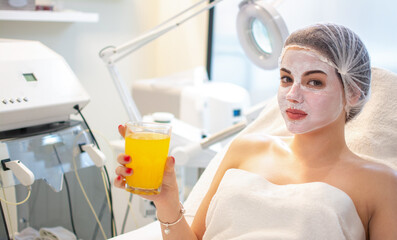 Beautiful young woman with facial mask relaxing at beauty salon.