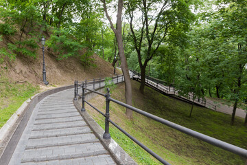 Paved path with railings on hillside in summer city park
