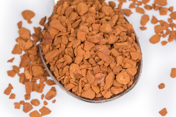 Instant coffee granules in spoon, close-up in selective focus