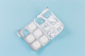 Partly used blister with square shape pills on blue surface