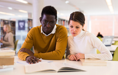 Obraz premium People reading and making notes while preparing for exam in library. High quality photo