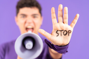 Stop message on hand of protestor shouting on megaphone isolated on purple background.