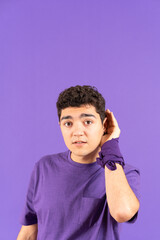 Hispanic teenager boy listening hand on ear isolated on purple background with copy space. Feminism concept