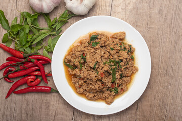 Pad kaprao, minced chicken in white plate on wooden background