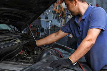 Car service, repair, maintenance and people concept - auto mechanic looking for a malfunction in...