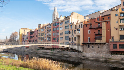 Fototapeta premium Colorful houses reflected in the Onyar river, in Girona, Catalonia, Spain. Church of Sant Feliu and Cathedral of Santa María in the background
