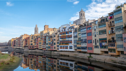 Colorful houses reflected in the Onyar river, in Girona, Catalonia, Spain. Church of Sant Feliu and Cathedral of Santa María in the background