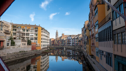 Colorful houses reflected in the Onyar river, in Girona, Catalonia, Spain. Church of Sant Feliu and Cathedral of Santa María in the background