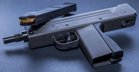 An UZI mini machine gun with a loaded, extended magazine on a black background