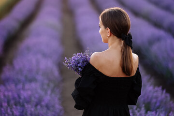 Back view of young romantic woman with healthy natural beauty skin holding bouquet in lavender...