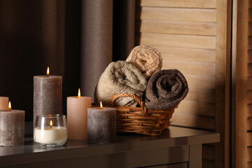 Fototapeta na wymiar Spa composition with burning candles and rolled towels on table in wellness center