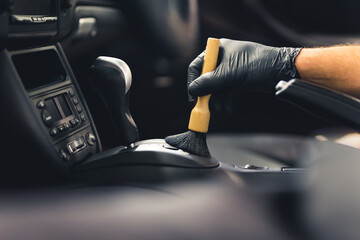 Man hand wearing protective glove, using cleaning brush and removing dust from gear shift knob....