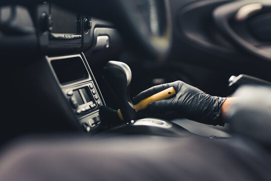 A man cleaning black car interior with a brush. Car detailing concept. Closeup shot with blurred foreground. High quality photo