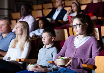 Obraz na płótnie Canvas Spectators eating popcorn and watching a movie at the cinema
