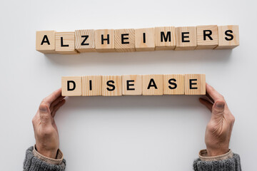 top view of cropped man touching wooden blocks with alzheimers disease inscription on white surface.