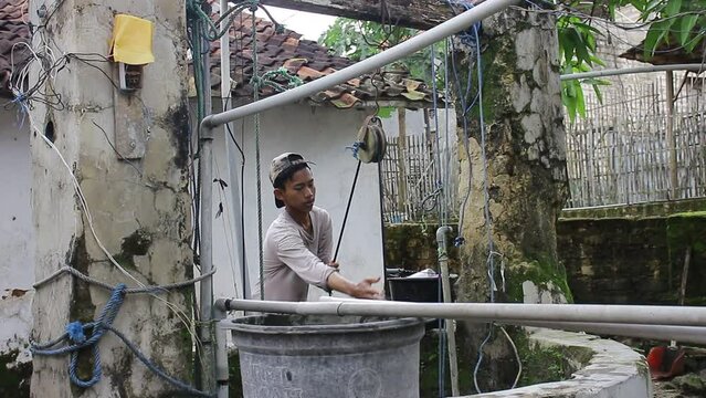 A Young Asian Who Is Drawing Water From A Well
