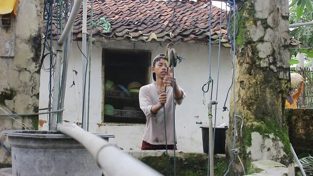A Young Asian Who Is Drawing Water From A Well