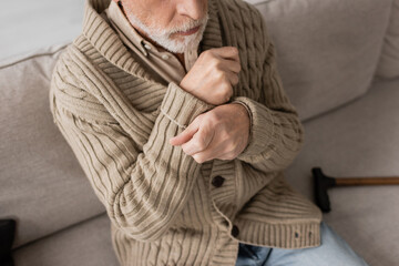 cropped view of senior man in knitted cardigan suffering from parkinsonism and tremor in hands...