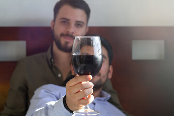 gay man with his partner raising glass of red wine