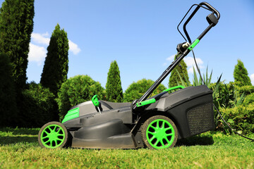 Fototapeta premium Lawn mower on green grass in garden