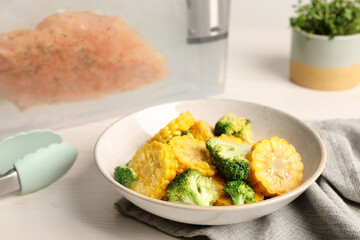 Bowl with delicious corn and broccoli on white wooden table. Sous vide cooking